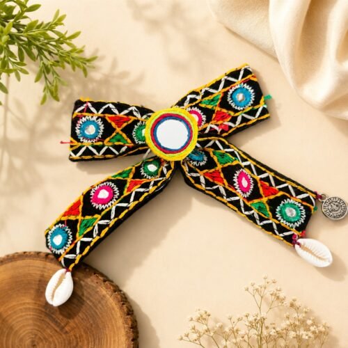 Close-up of mirror-work hair bow with cowrie shell and charm tassels