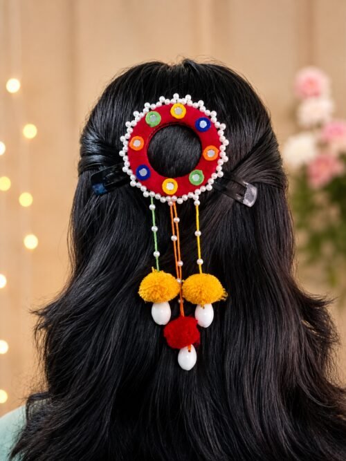 Red mirror-work hair ornament with marigold pom-poms and pearl trim