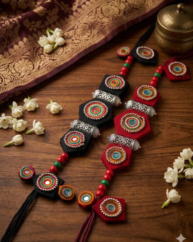 Black and red thread-wrapped mirror-work medallion necklaces styled on wood and silk
