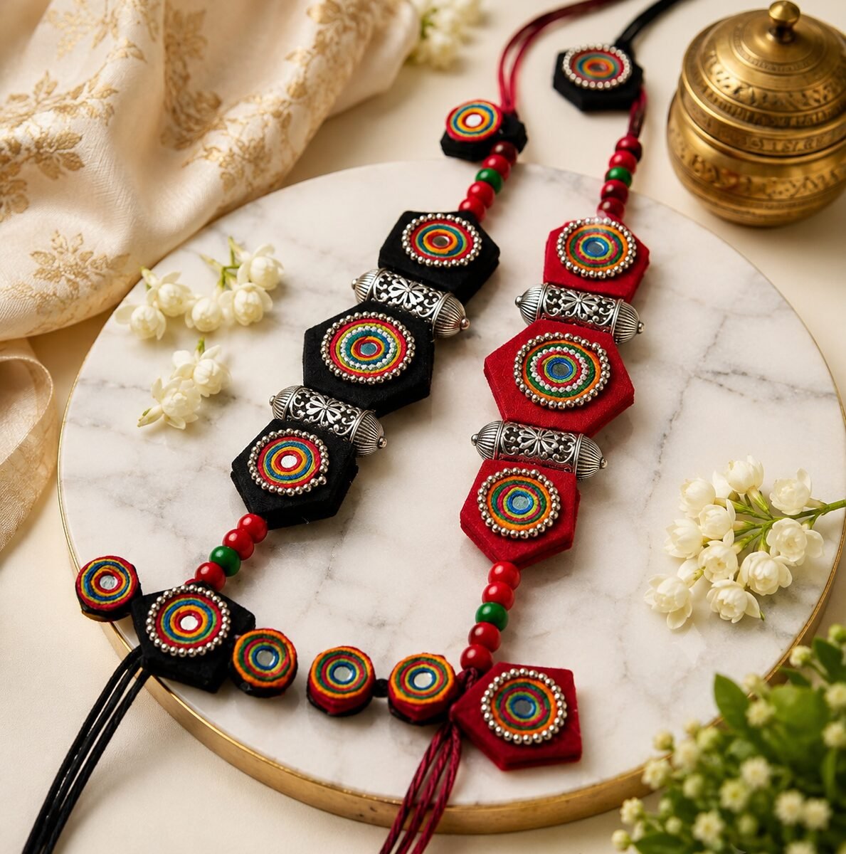 Black and red medallion necklaces styled on marble with brass and jasmine