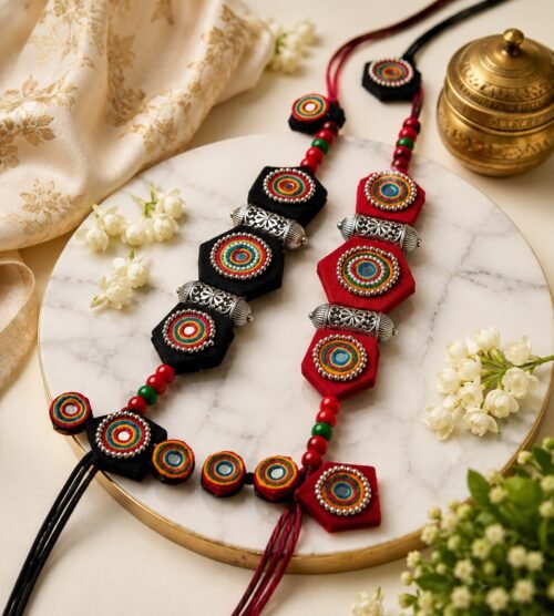 Black and red medallion necklaces styled on marble with brass and jasmine