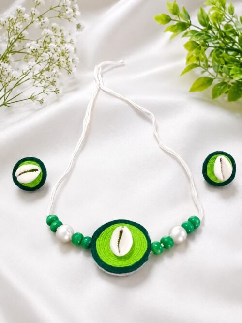 Green thread-wrapped cowrie shell necklace and earring set on white satin