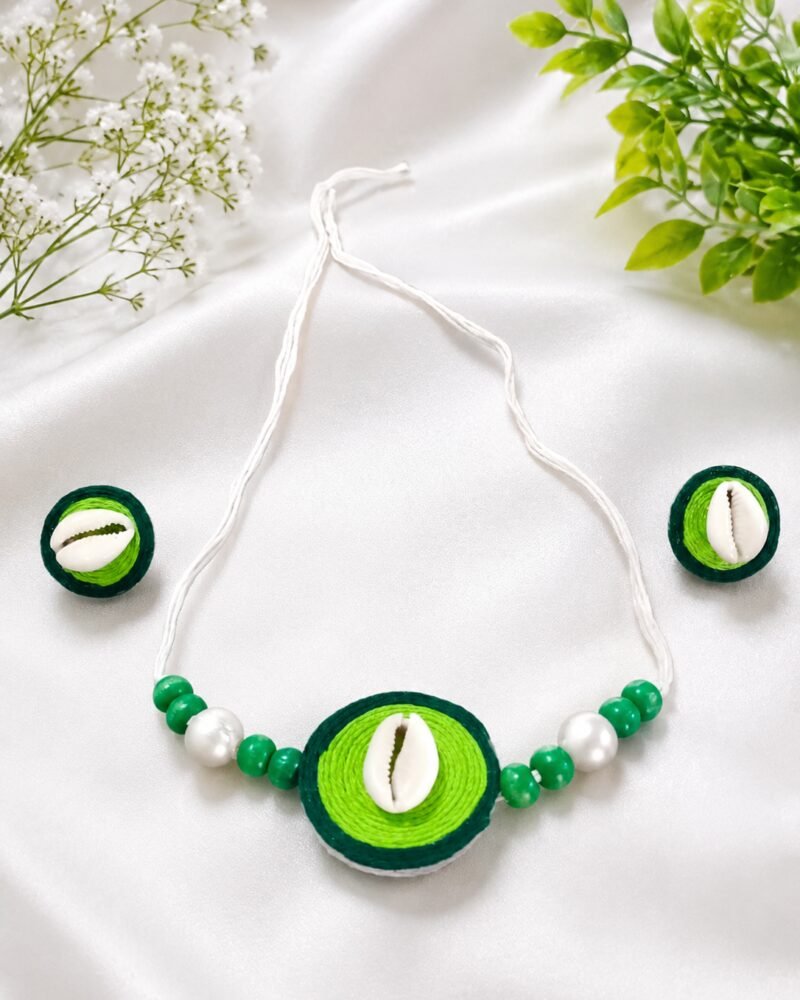 Green thread-wrapped cowrie shell necklace and earring set on white satin